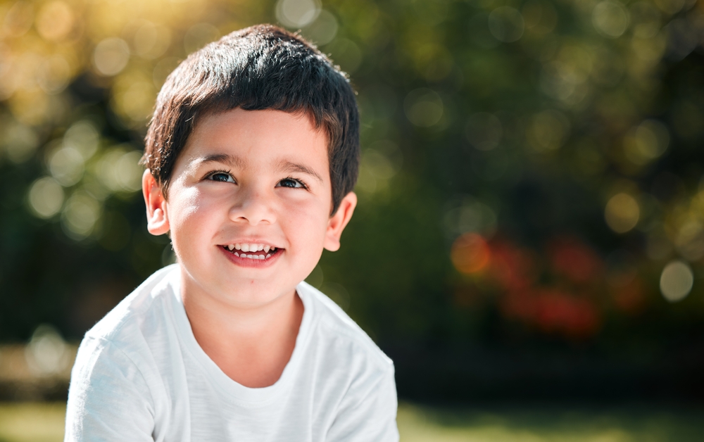 Young child smiling brightly outside with clean, healthy teeth, representing positive dental care experiences in pediatric dentistry - Pediatric Dentistry San Diego