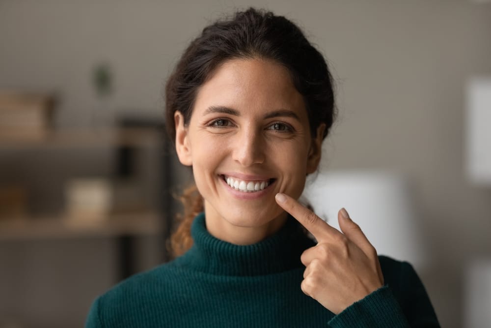 Woman pointing at her bright white teeth, showcasing successful teeth whitening results in San Diego – Teeth Whitening San Diego