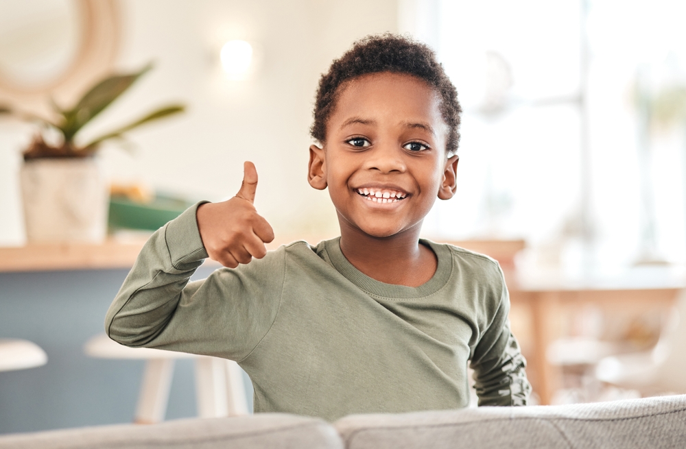 Smiling child giving a thumbs up while showing healthy teeth, representing positive experiences and successful care in pediatric dentistry - Pediatric Dentistry San Diego