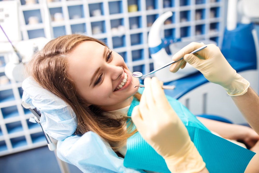 Female patient smiling during a dental procedure while a dentist uses tools in a modern clinic, illustrating a comfortable root canal treatment experience - Root Canal San Diego