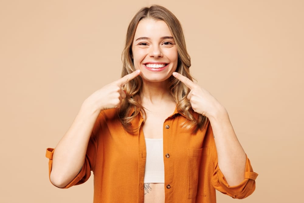Smiling woman pointing at her white teeth highlighting results of professional teeth whitening treatment in La Mesa – Teeth Whitening La Mesa